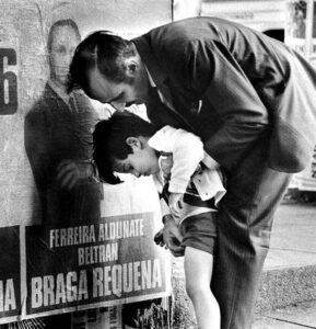 Romano%2BCagnoniUruguay%252C%2B1971.%2BA%2Bfather%2Bhelps%2Bhis%2Bboy%2Bto%2Bpee%2Bon%2Bthe%2Bportrait%2Bof%2Ba%2Bpolitician%2Bduring%2Bthe%2Belections%2Bin%2BMontevideo.jpg