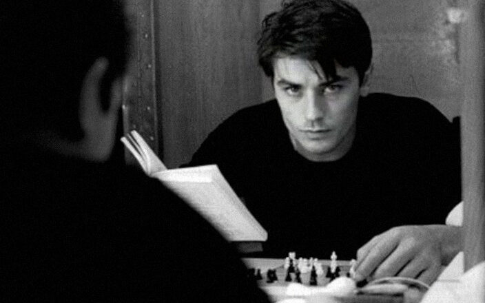 Alain-Delon-reading-a-book-and-playing-with-himself