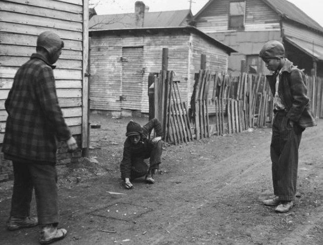 Three boys play marbles in a dirt alley 1930s